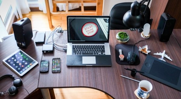 Photo of a work desk with a laptop, phone and iPad, tying into the article about oil and natural gas being used to make everyday products.